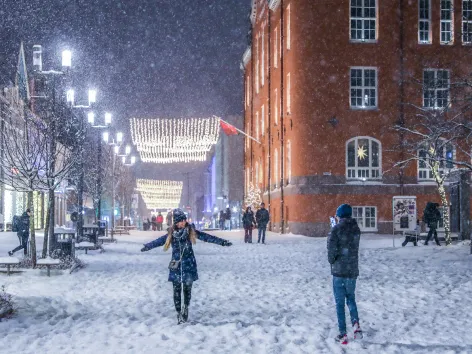 Two persons enjoying themselves in the snowy main street Storgata in Tromsø