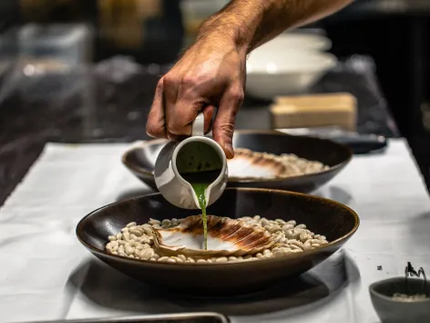 Chef pouring sauce for a scallop meal