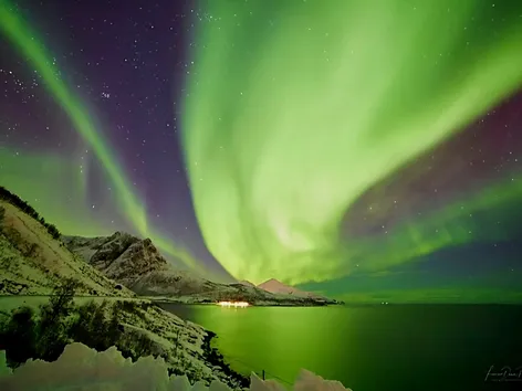 Northern lights above mountains and ocean in the Tromso region in winter