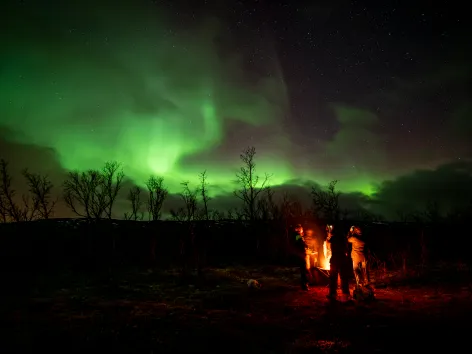 Guests standing besides a bonfire