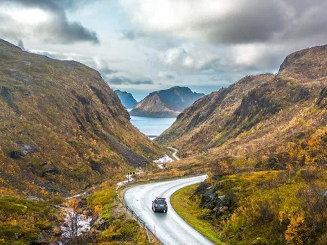 En bil som kjører på en vei gjennom fjellterreng på Senja