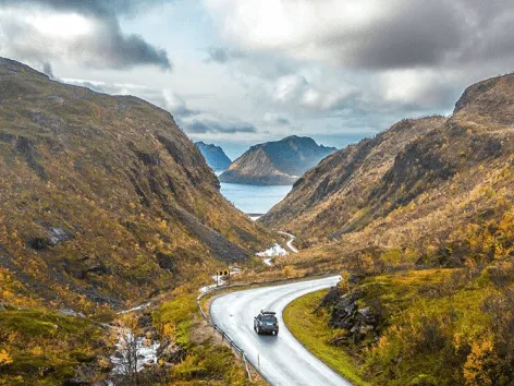 A car driving on a road through mountainous terrain in Senja