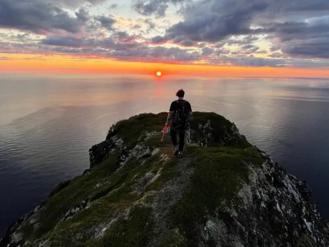 man on top of a mountain watching the sunset 