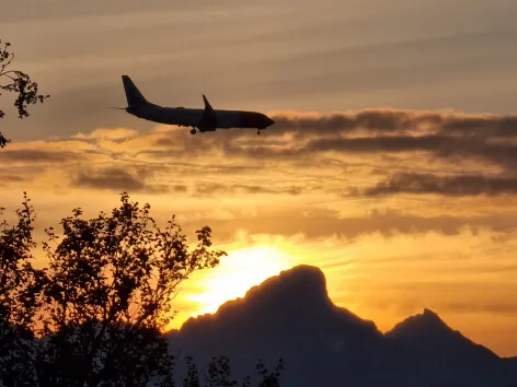 An airplane in the sky with sunset in the background.