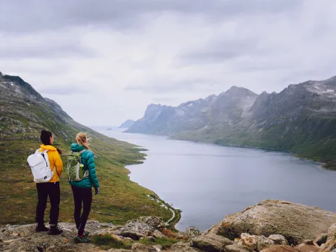 Two people standing on a mountain looking a the landscape.