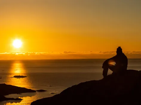 man watching the sunset over the sea during the midday sun