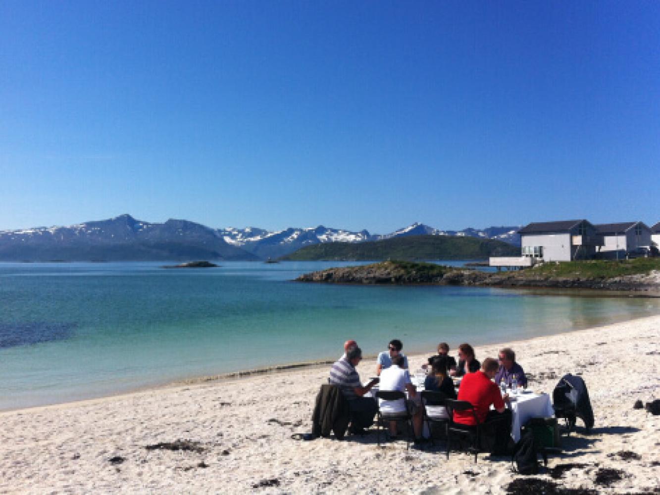 MICE-gjester nyter et måltid på en strand på Sommarøy utenfor Tromsø