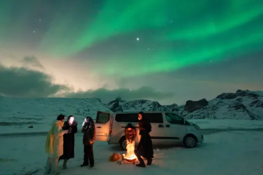 Noen gjester foran minibussen og ser på nordlyset