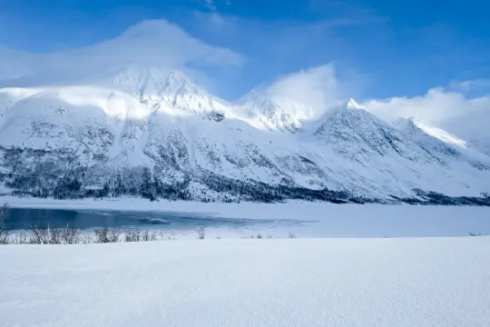 Snowy mountains behind icy lake