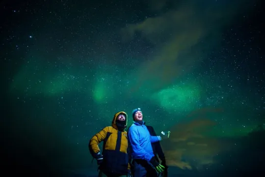 Two persons enjoying northern lights in the Tromso regionh