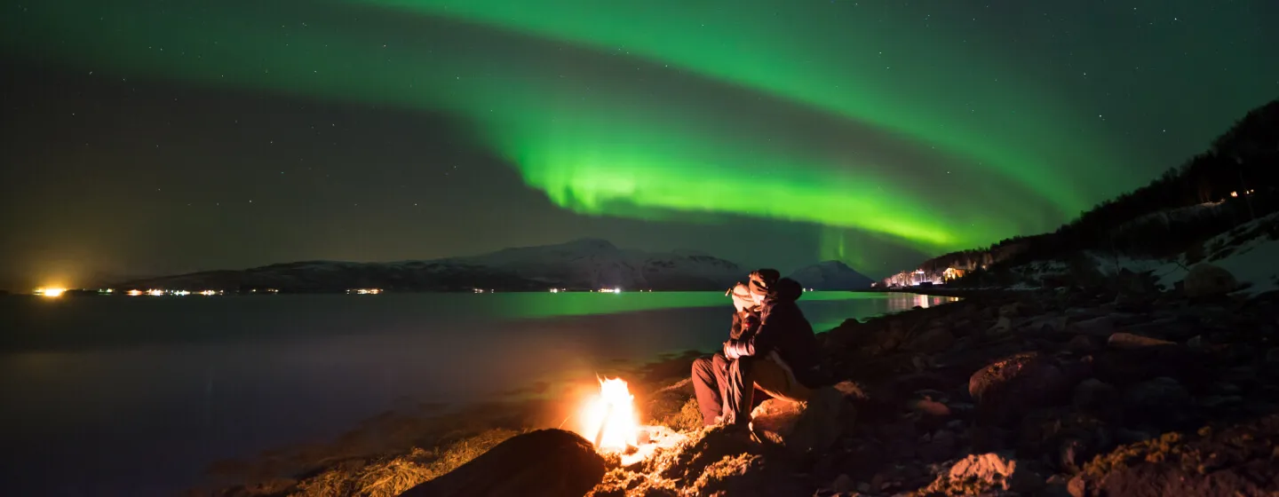 Enjoying the northern lights around a bonfire at the beach