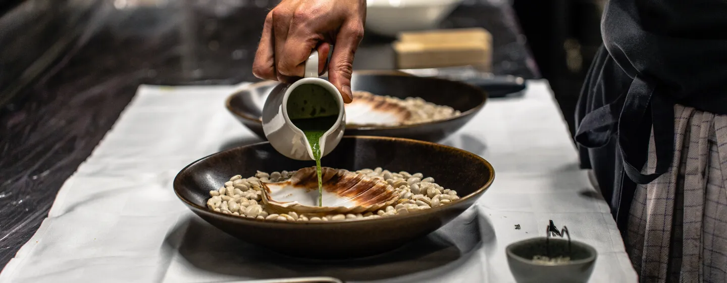 Chef pouring sauce for a scallop meal