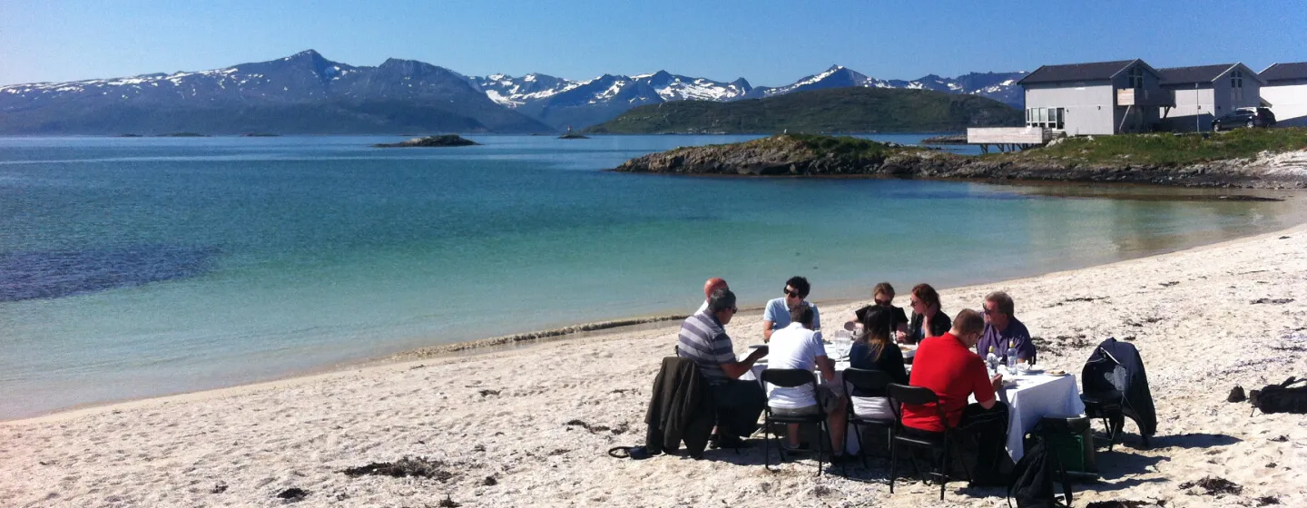 MICE-gjester nyter et måltid på en strand på Sommarøy utenfor Tromsø