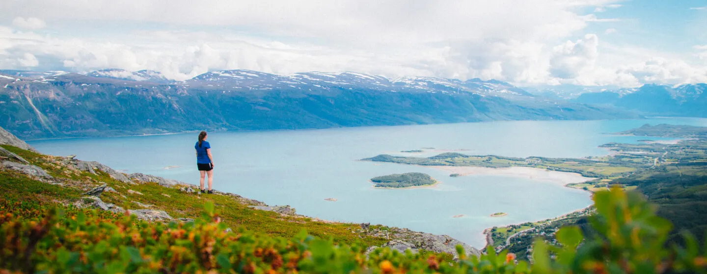 En person som nyter utsikten fra en fjelltopp i Tromsøregionen