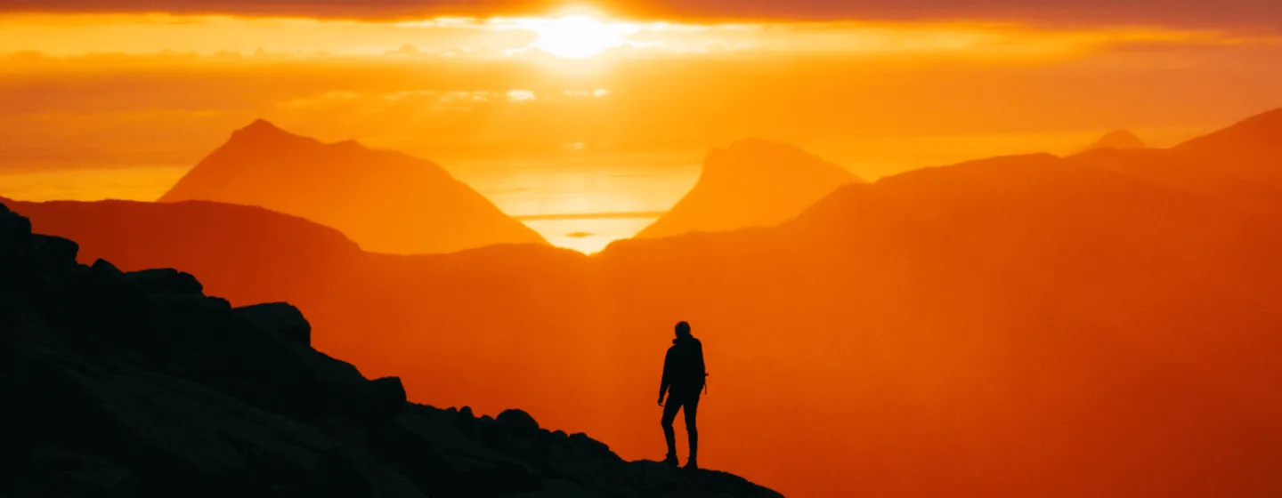 Silhouette looking at sunset from mountain peak on Kvaløya