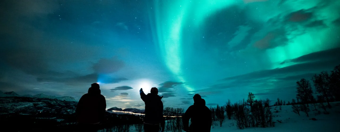 Tre mennesker beundrer nordlyset