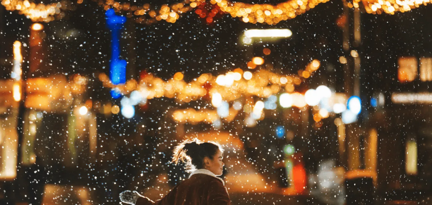 Woman dancing in the snow with Christmas lights