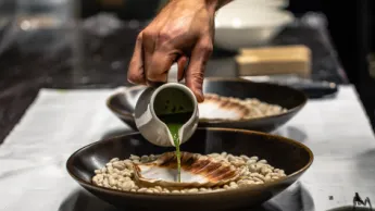 Chef pouring sauce for a scallop meal